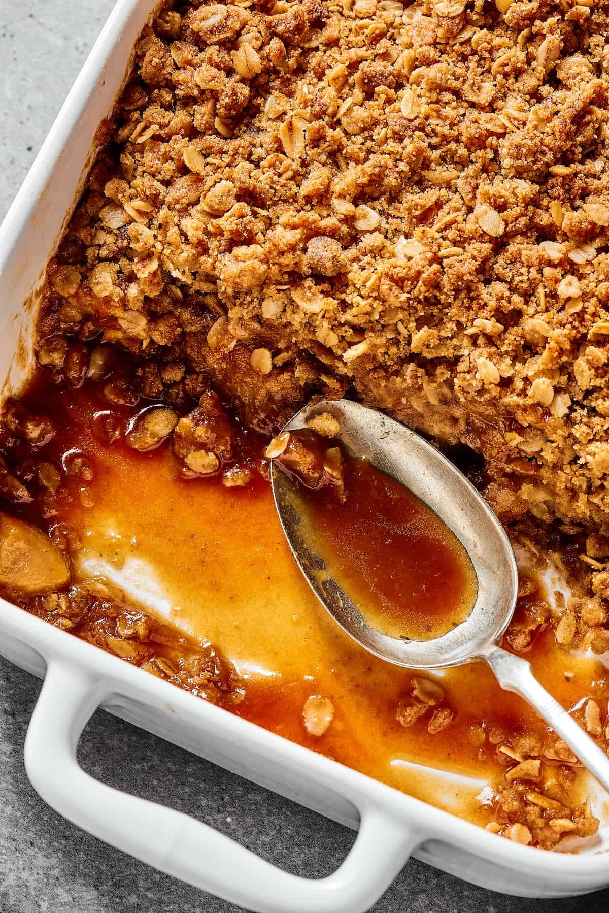 Close-up shot of a golden-brown apple crisp cobbler, showing the texture of the topping and the juicy apples underneath