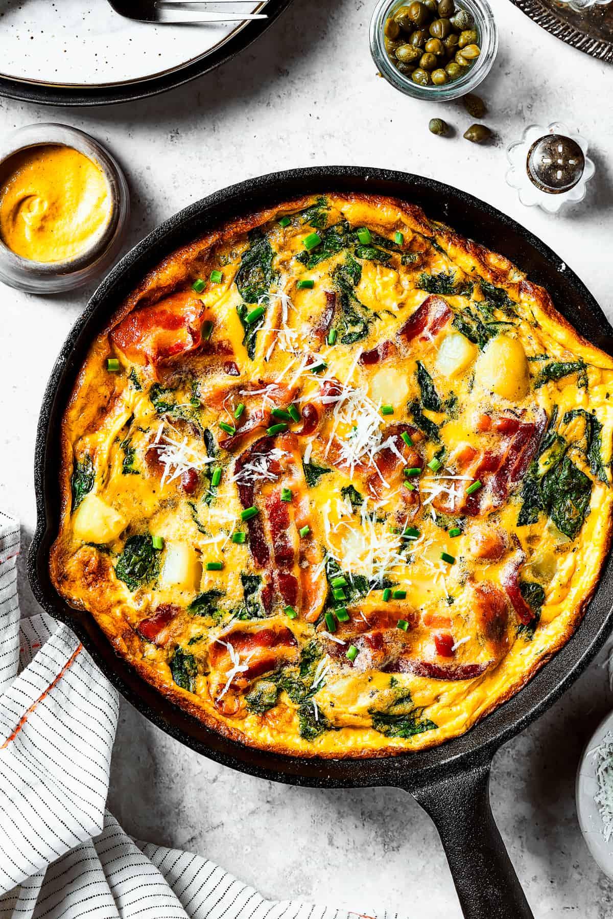 Overhead shot of a frittata cooking in a skillet on a stovetop