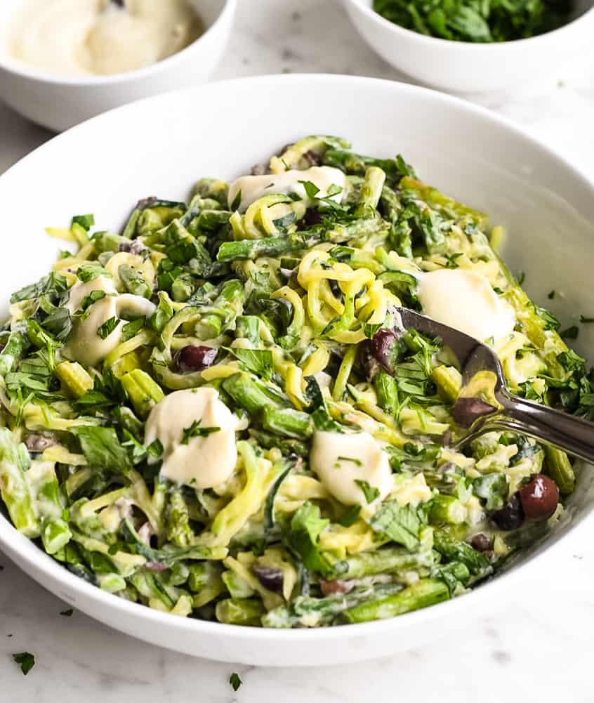 A vibrant image of garlic parmesan zucchini noodles with asparagus, showcasing the bright green asparagus and yellow zucchini noodles tossed in a creamy parmesan sauce.