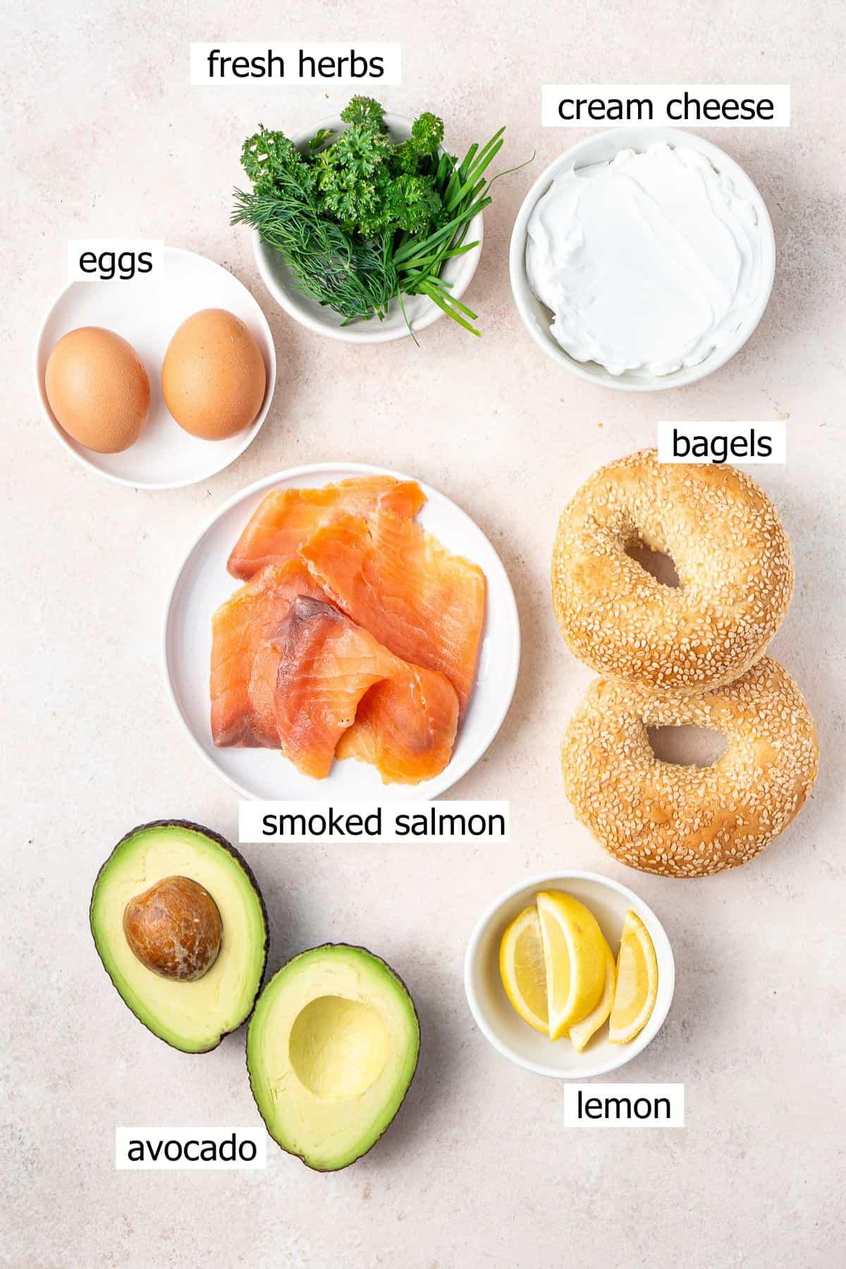 Various ingredients laid out next to a bagel; cream cheese, smoked salmon, dill