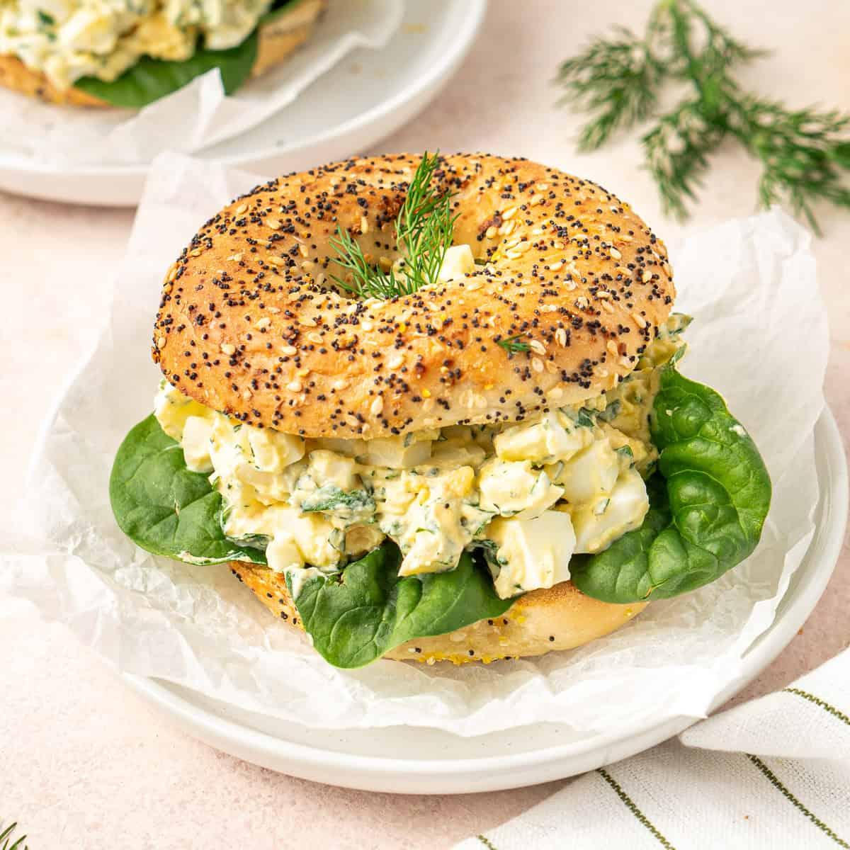 Close-up shot of a bagel with egg salad and lettuce, showcasing fresh ingredients and vibrant colors