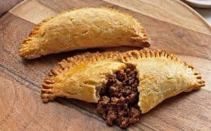Close-up shot of golden-brown Panamanian Sancocho-inspired empanadas on a baking sheet