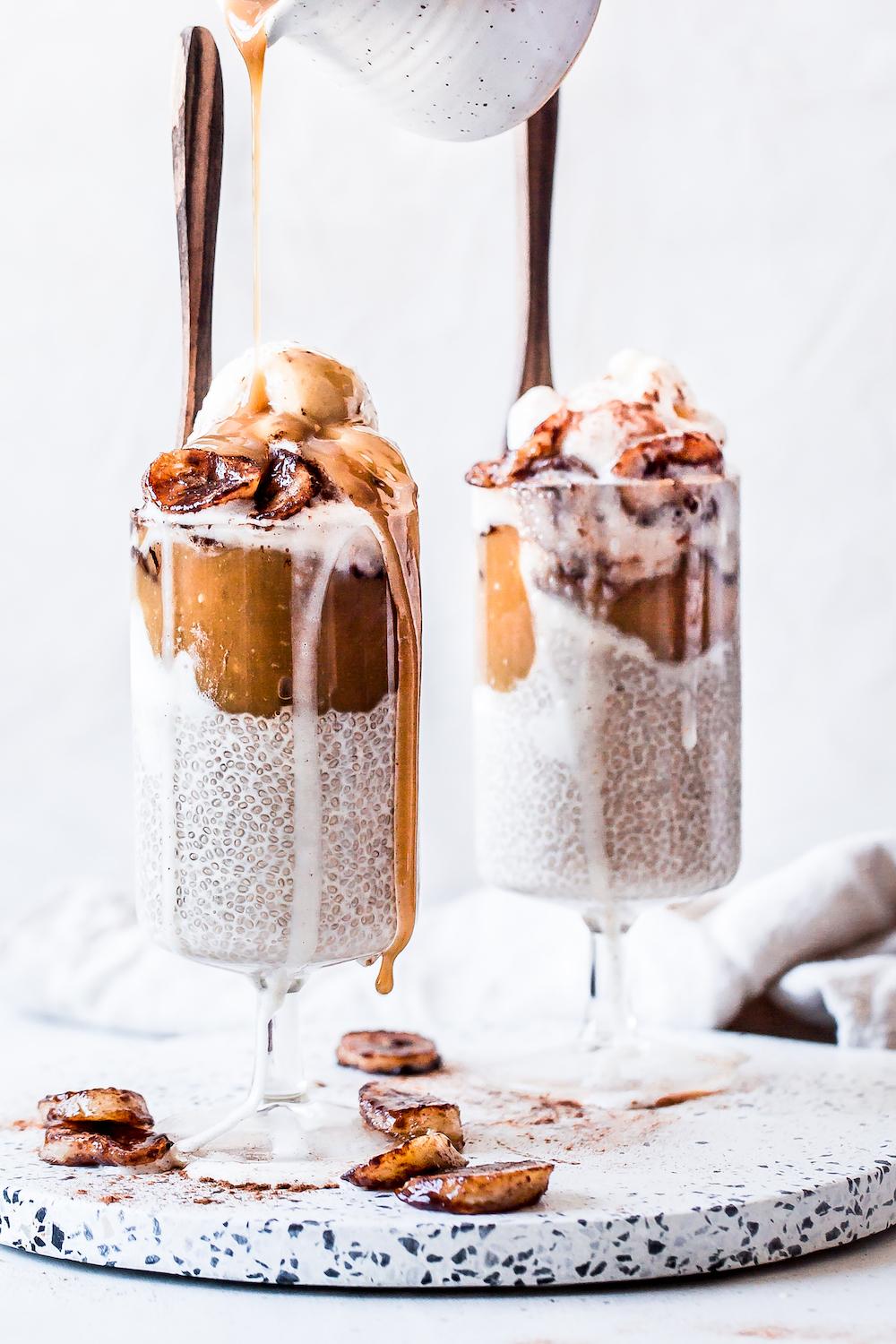 Close-up shot of four glasses of layered banana foster chia pudding with caramelized bananas on top