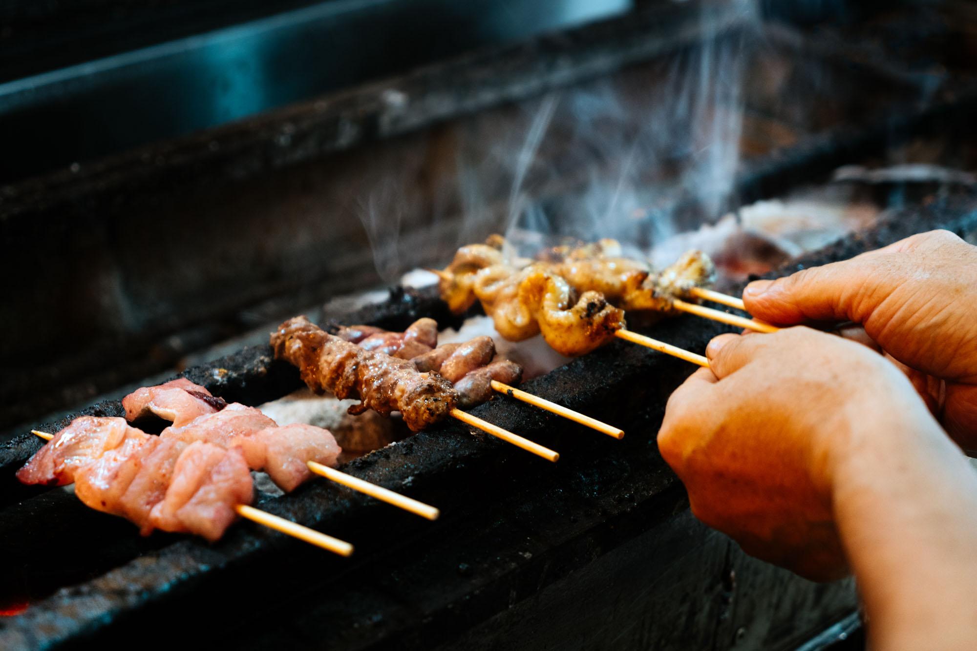 close up of a person grilling eel skewers outdoors