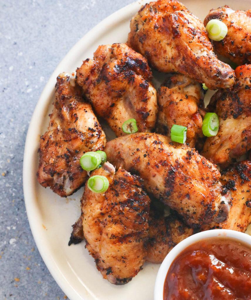 Close-up shot of a person applying dry rub to chicken wings