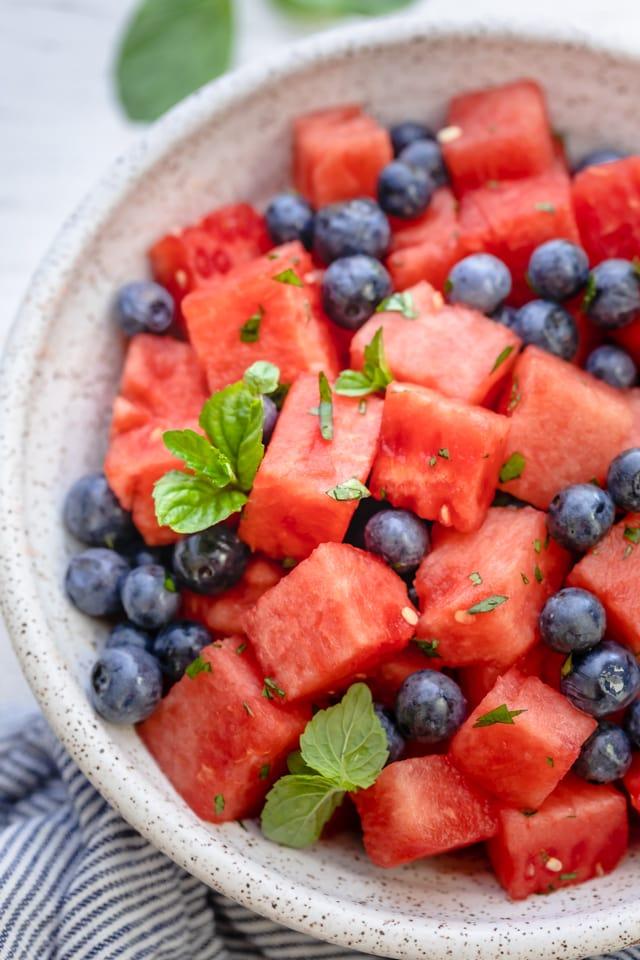 Close-up shot of a watermelon salad with blueberries and lemon slices.