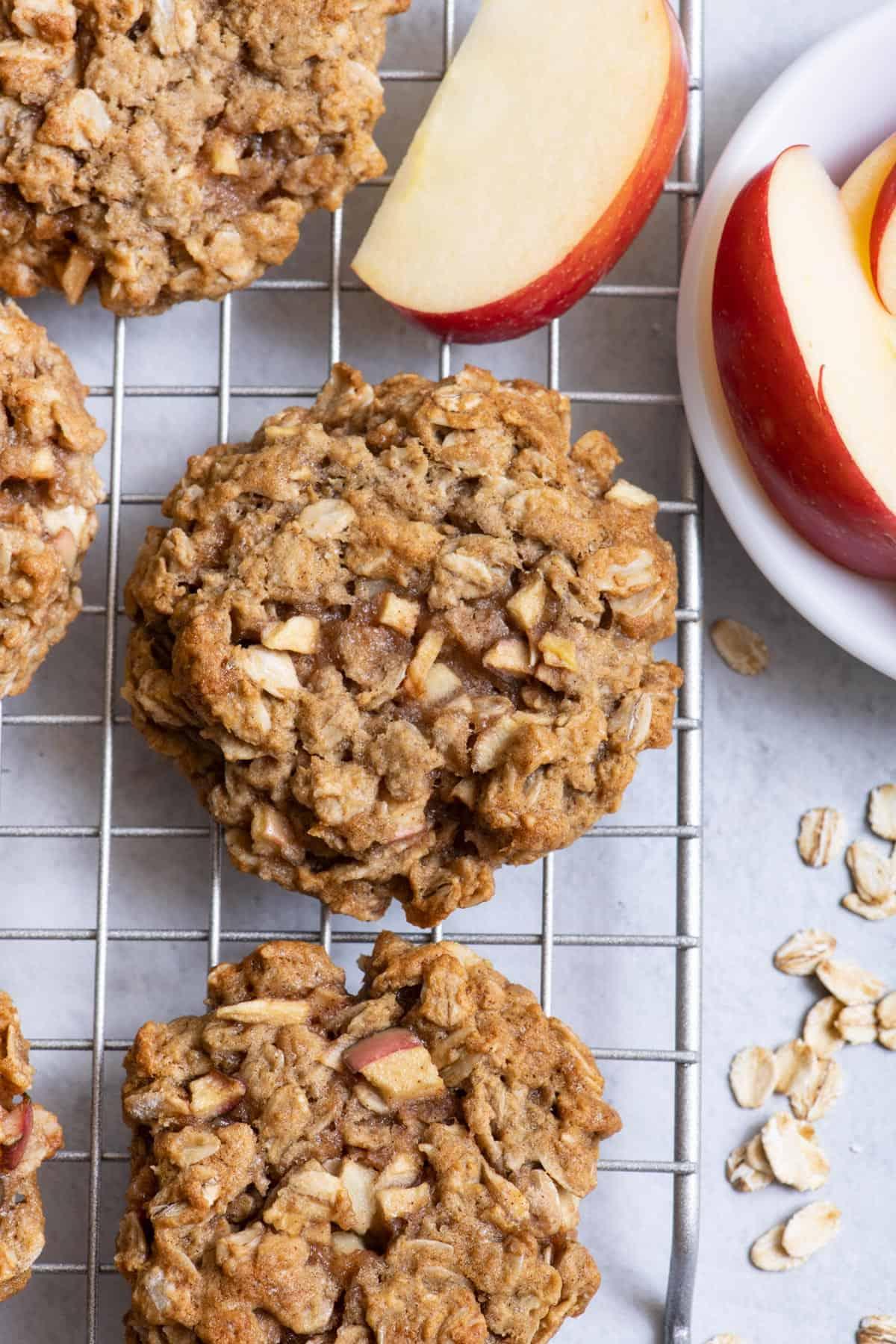 a batch of freshly baked apple oatmeal cookies with chocolate chips cooling on a wire rack
