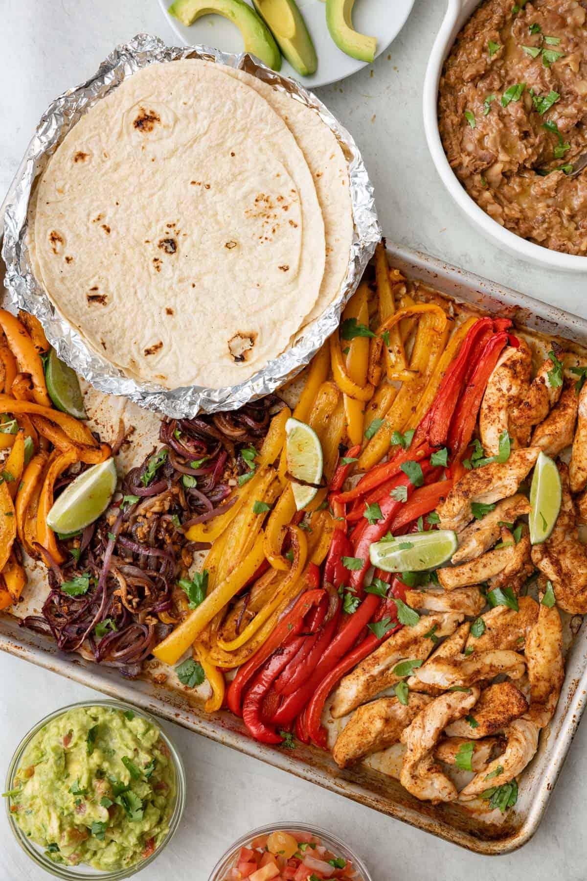 A table set with several Chicken Fajita Burritos, garnished with fresh cilantro and lime wedges