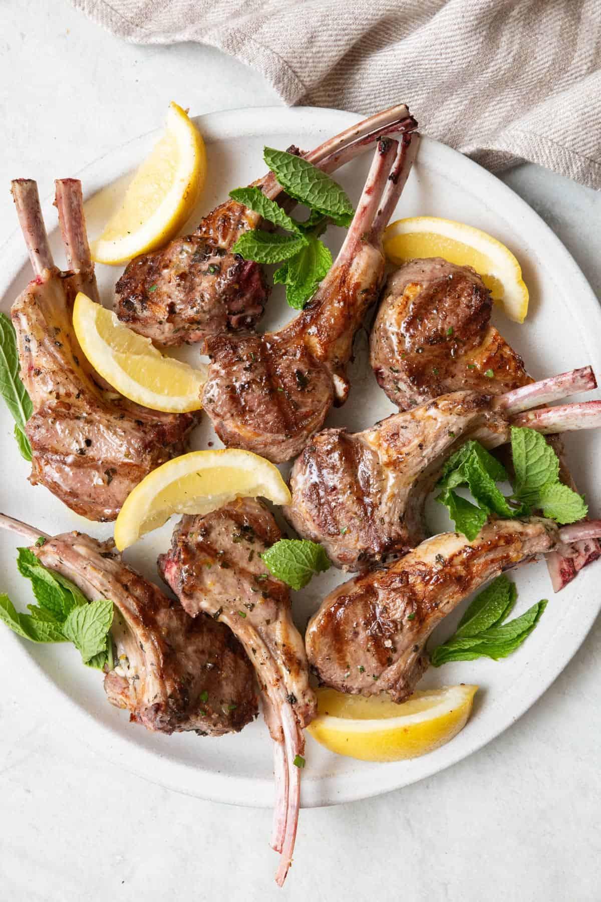 Close-up of juicy Mediterranean grilled lamb chops with lemon wedges and herbs