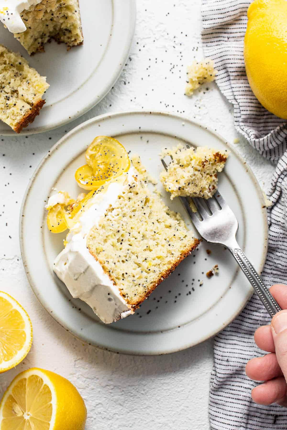 A person serving a slice of lemon poppy seed cake on a plate