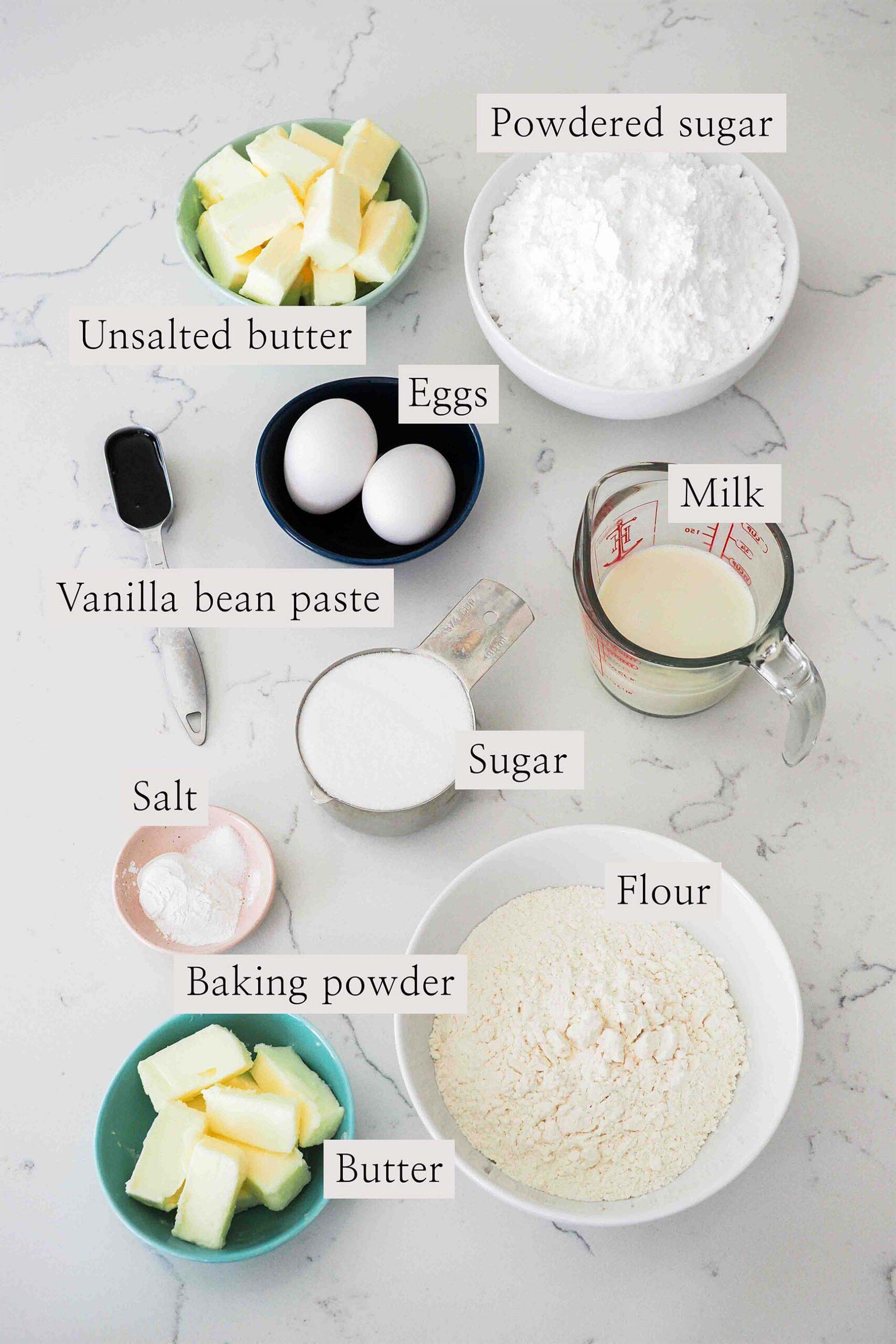 ingredients laid out for vanilla bean cupcakes, including flour, sugar, butter, and vanilla beans