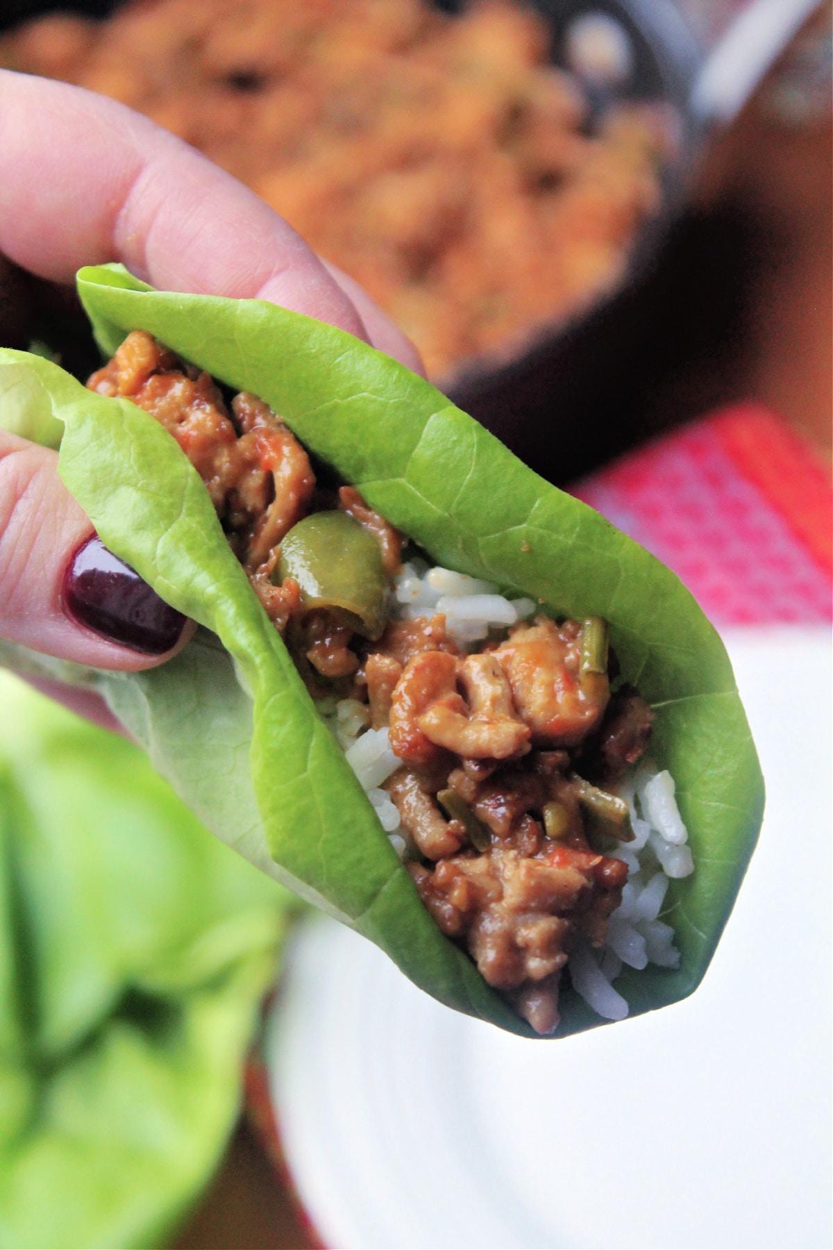 close up of a person assembling chicken lettuce wraps