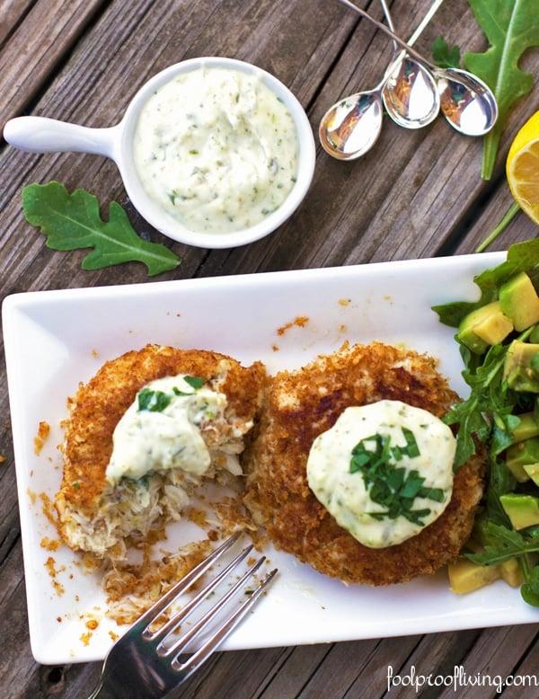 overhead shot of a plate with two crab cakes, remoulade sauce, and a fresh salad