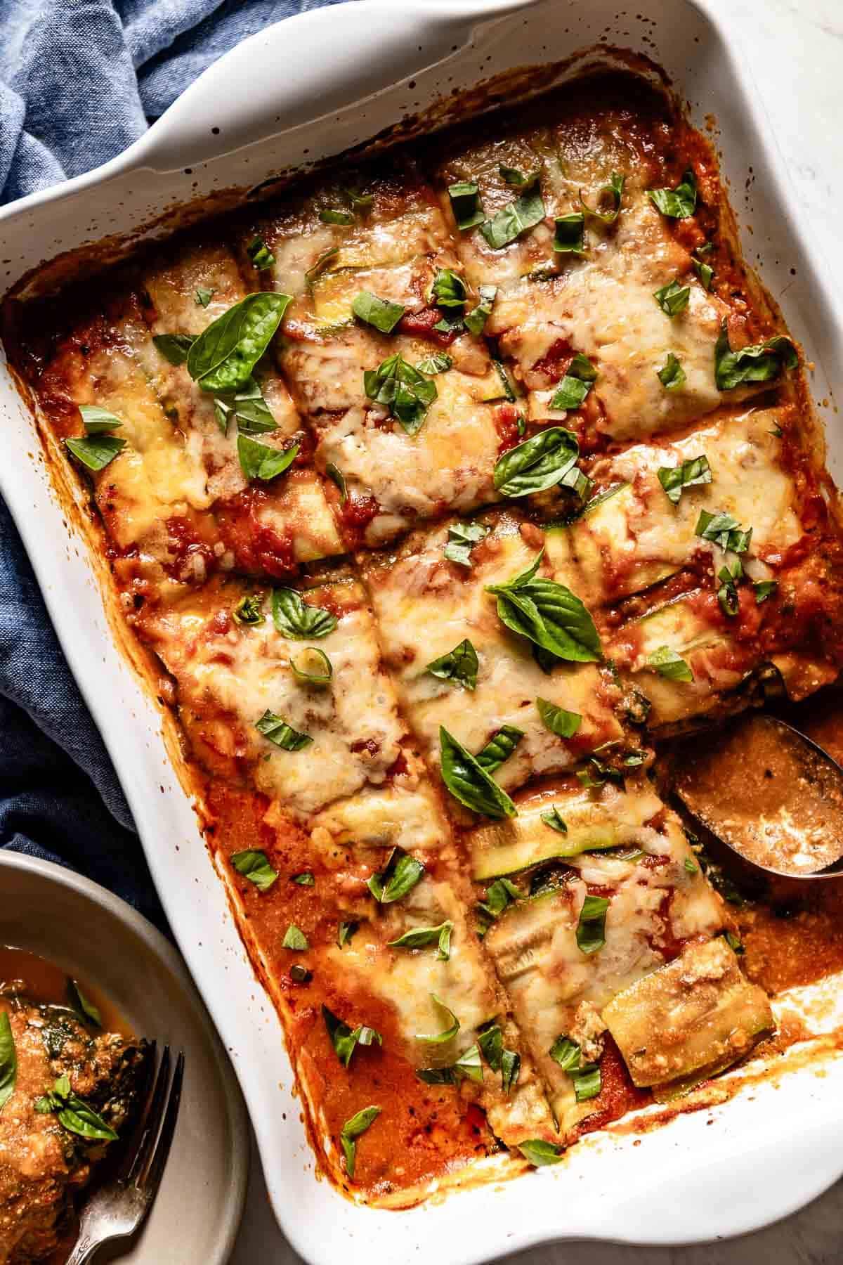 A delicious-looking zucchini lasagna with a creamy, cheesy filling, garnished with fresh basil.
