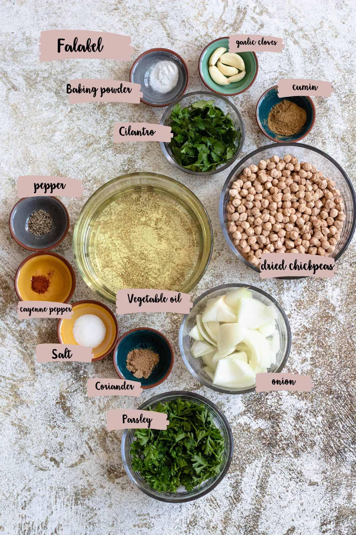Overhead shot of a variety of falafel ingredients, including dried chickpeas, nori sheets, fresh herbs, and spices.