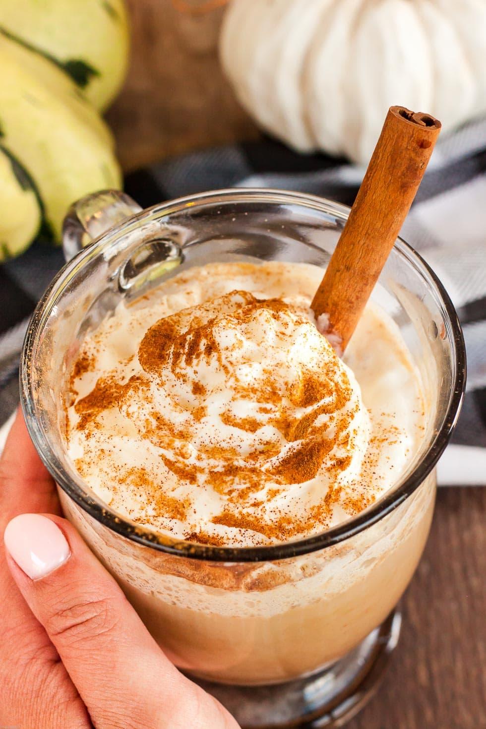 Close up of a hand holding a glass of pumpkin spice latte smoothie