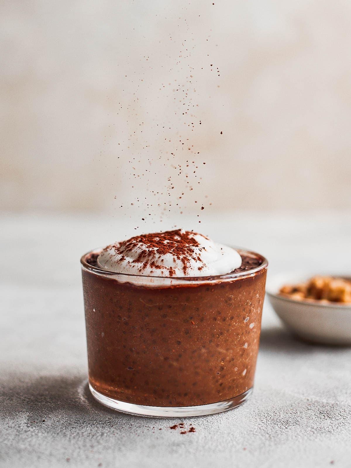 Close-up shot of chocolate avocado chia pudding with cocoa nibs in a glass jar
