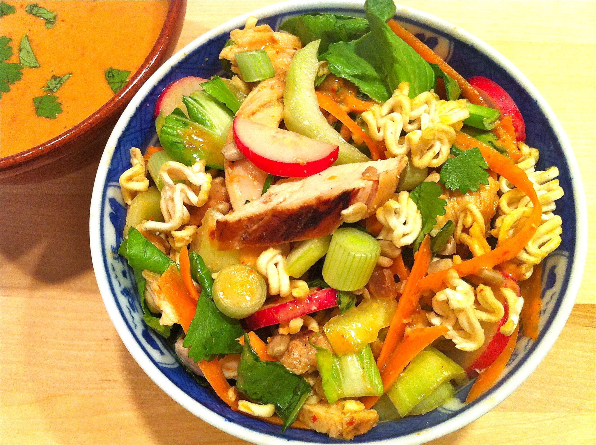 Close-up of someone tossing Bok Choy and Peanut Noodle Salad in a large bowl