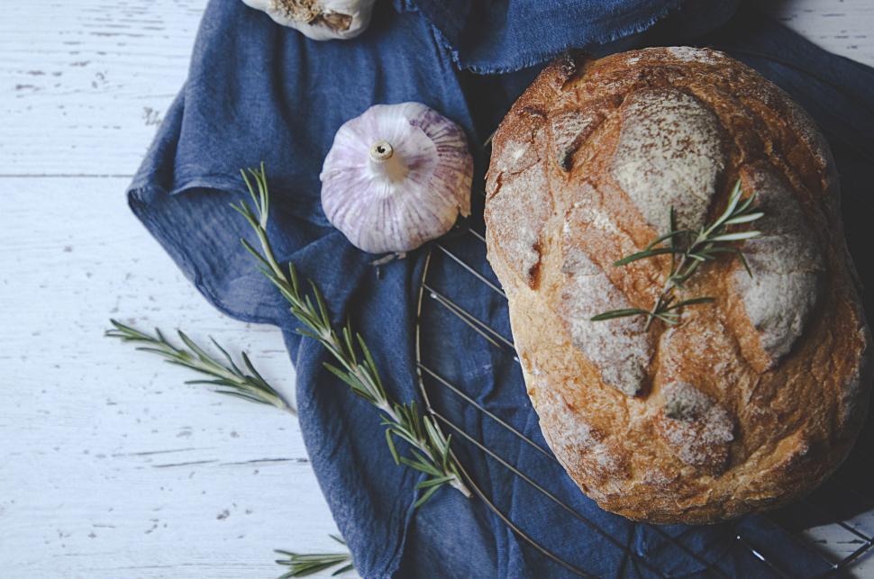 A rustic scene of a sourdough loaf cooling on a wire rack, with a basket of ancient grains in the background.