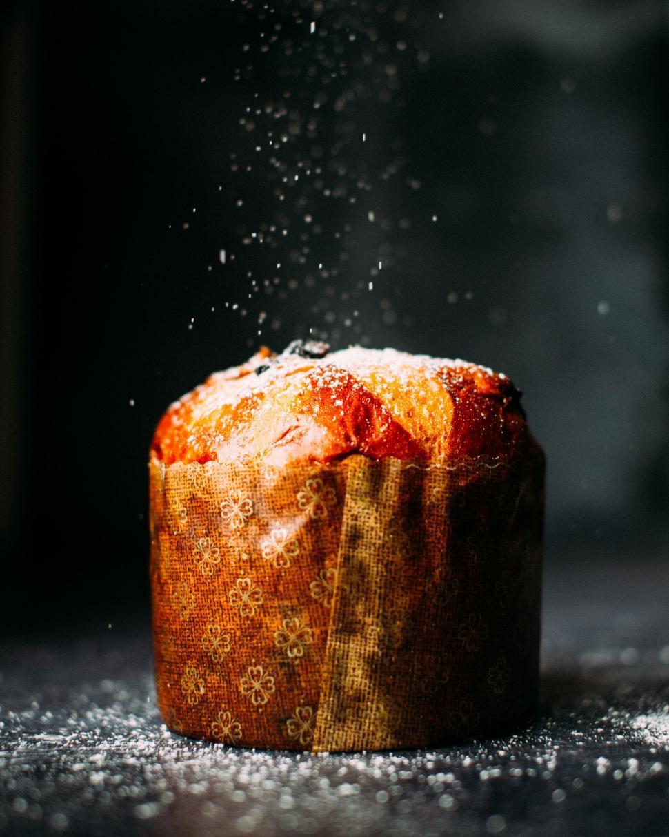 Close-up shot of a golden-brown sourdough panettone with a dusting of powdered sugar