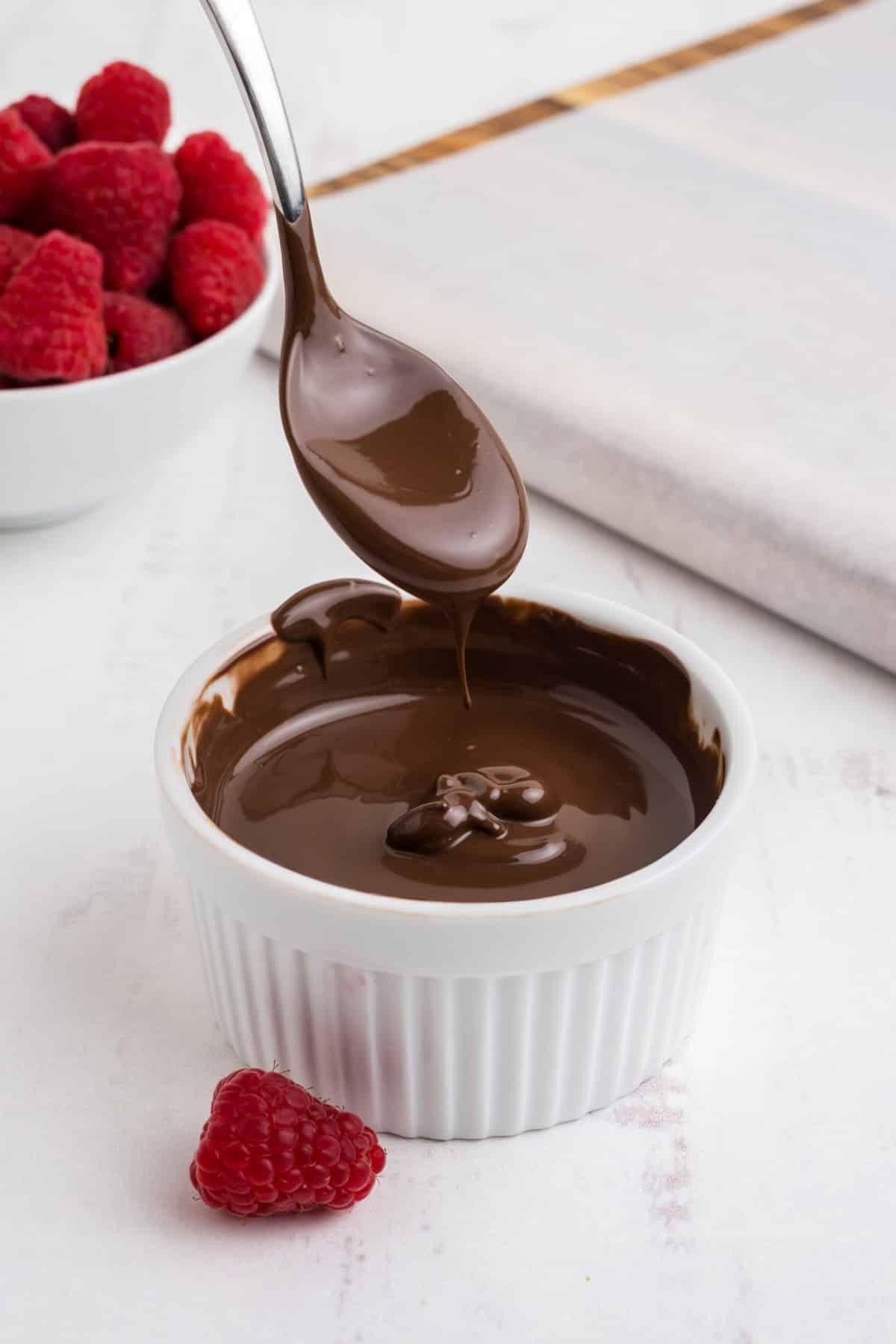 Close-up shot of a chocolate covered raspberry dripping with melted chocolate
