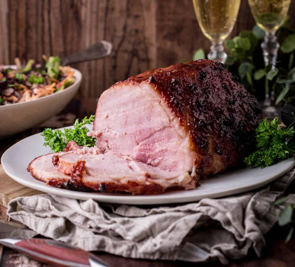 Close-up shot of a glistening coffee-rubbed Christmas ham with a rich molasses glaze, garnished with fresh cranberries