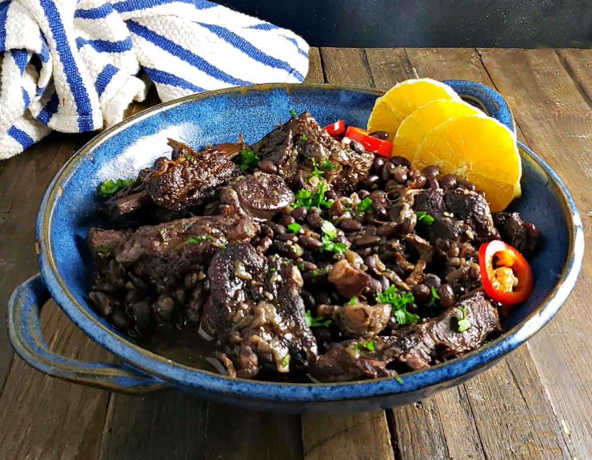 Close-up shot of feijoada simmering in a pot, showcasing the liverwurst and pickle chunks