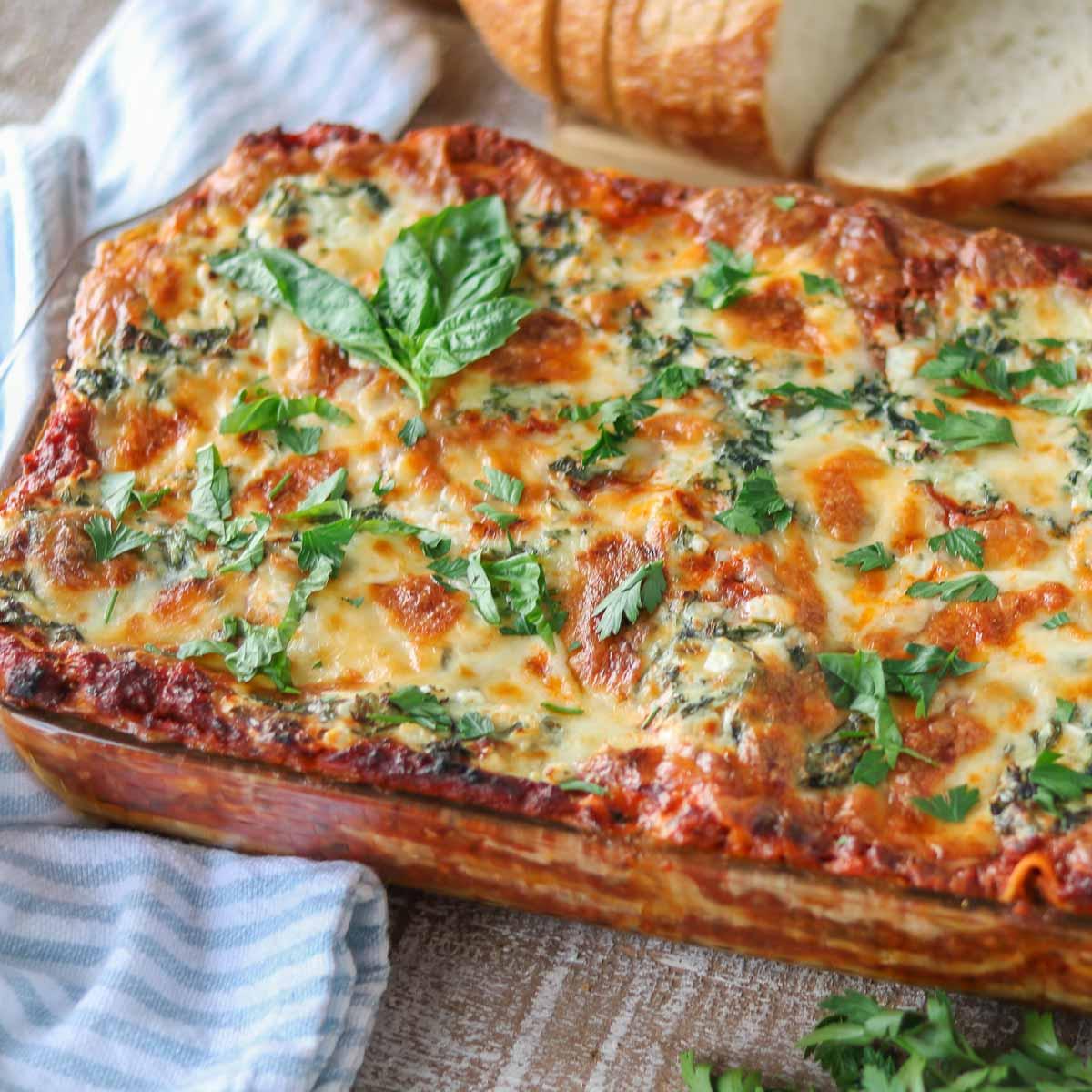 baked camel lasagna, sliced and plated, garnished with fresh herbs