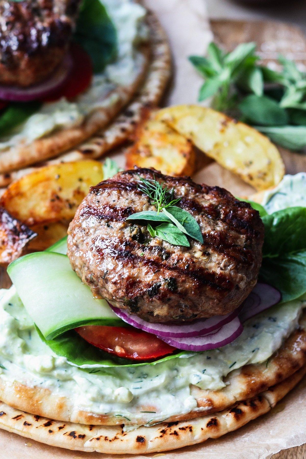 close-up of a juicy grilled lamb patty topped with avocado crema and fresh toppings