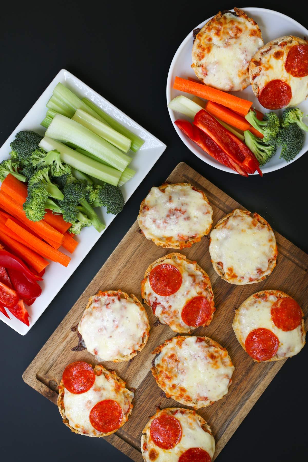 A table set with several mini pizzas, alongside a fresh salad