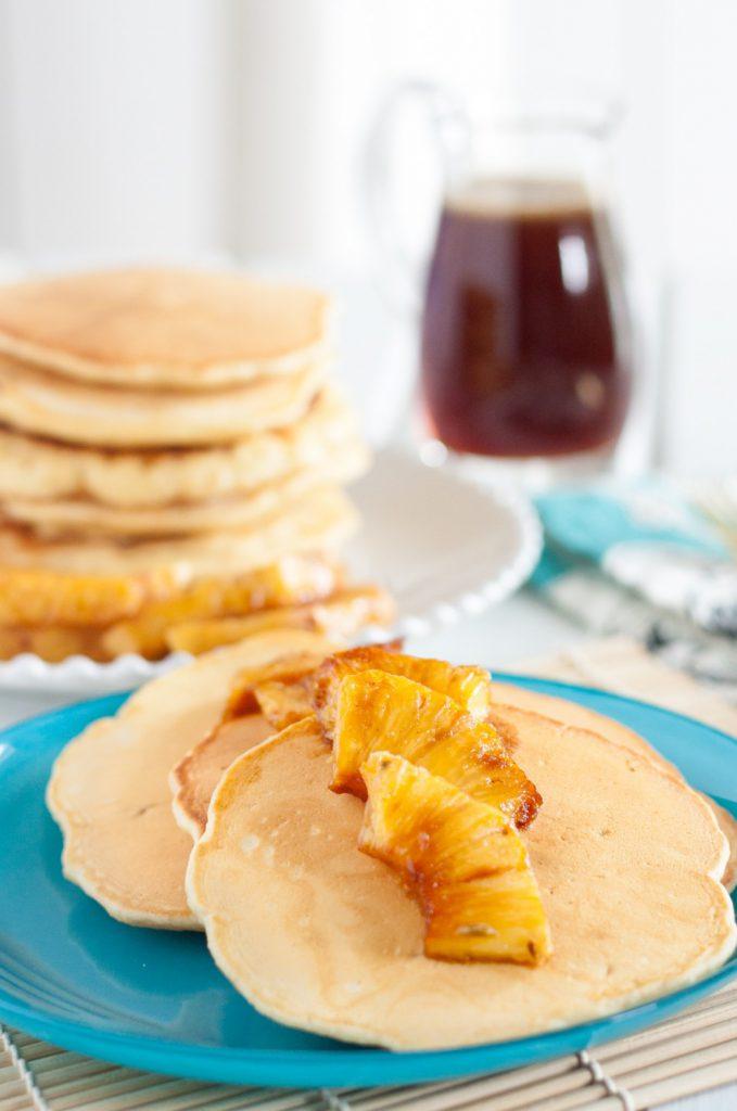 Person enjoying a stack of pineapple pancakes with a cup of coffee