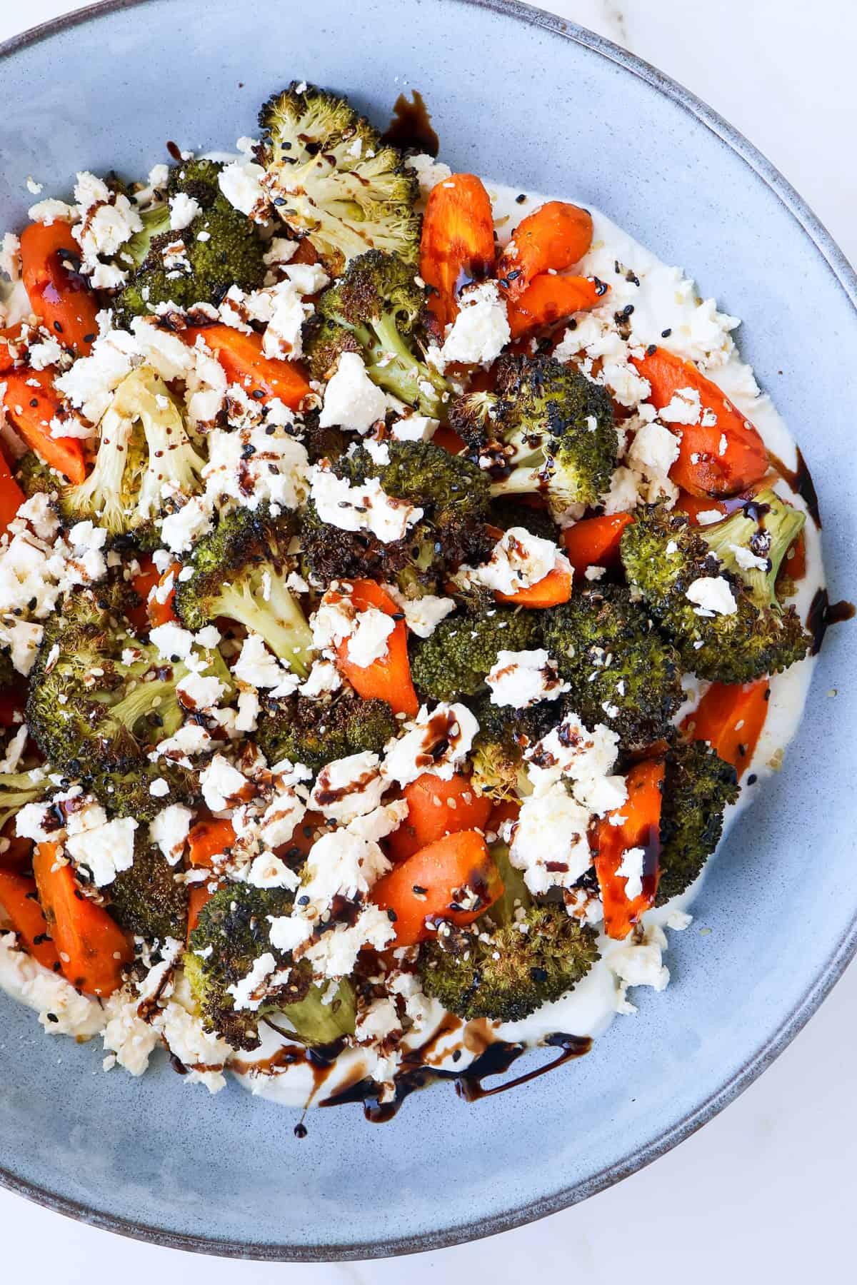 Close-up shot of a bowl of colorful roasted vegetables with crumbled feta cheese.