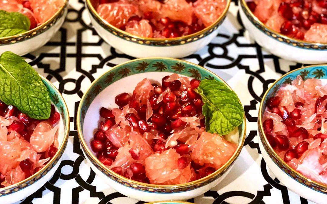 a person enjoying a bowl of pomelo and pomegranate salad on a sunny patio