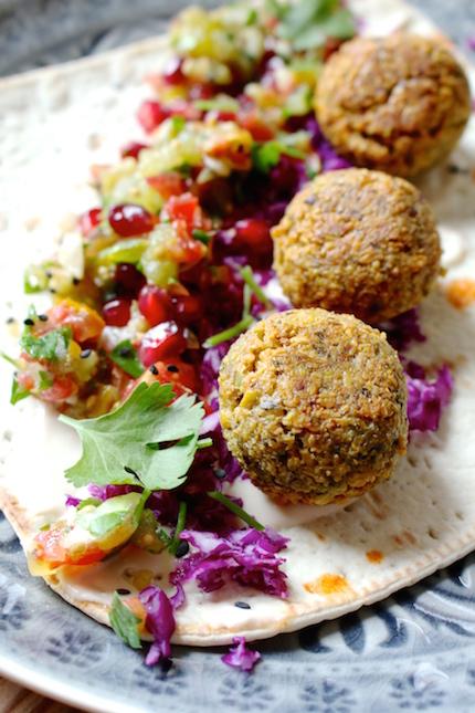 Close-up shot of crispy falafel drizzled with pomegranate-mint dressing