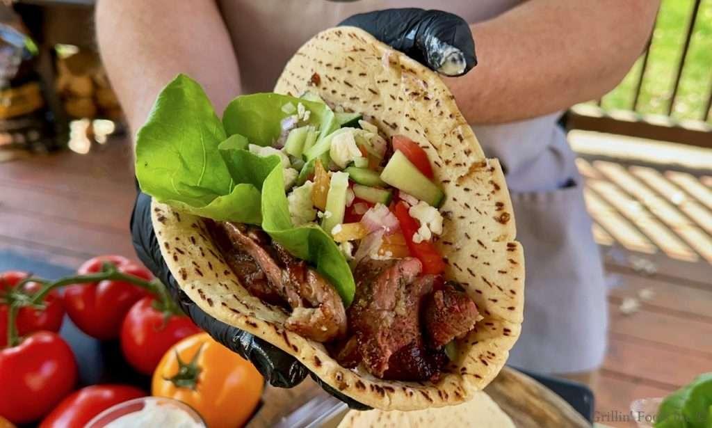 A close up image of a finished lamb gyro being held by a person