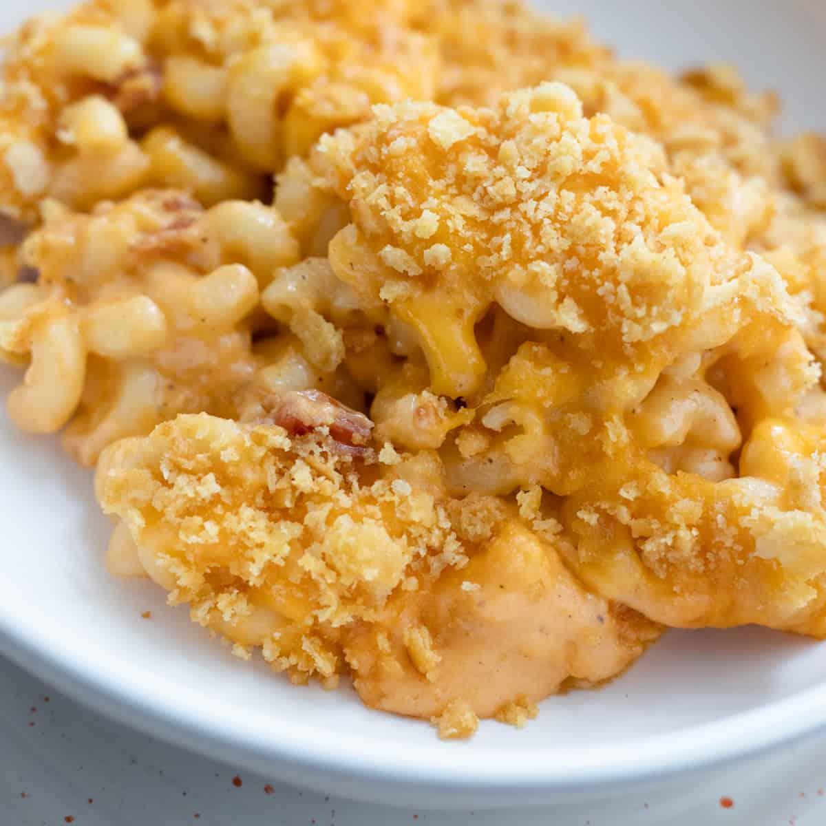 a bowl of mac and cheese ice cream with various toppings like bacon bits and cheese crackers
