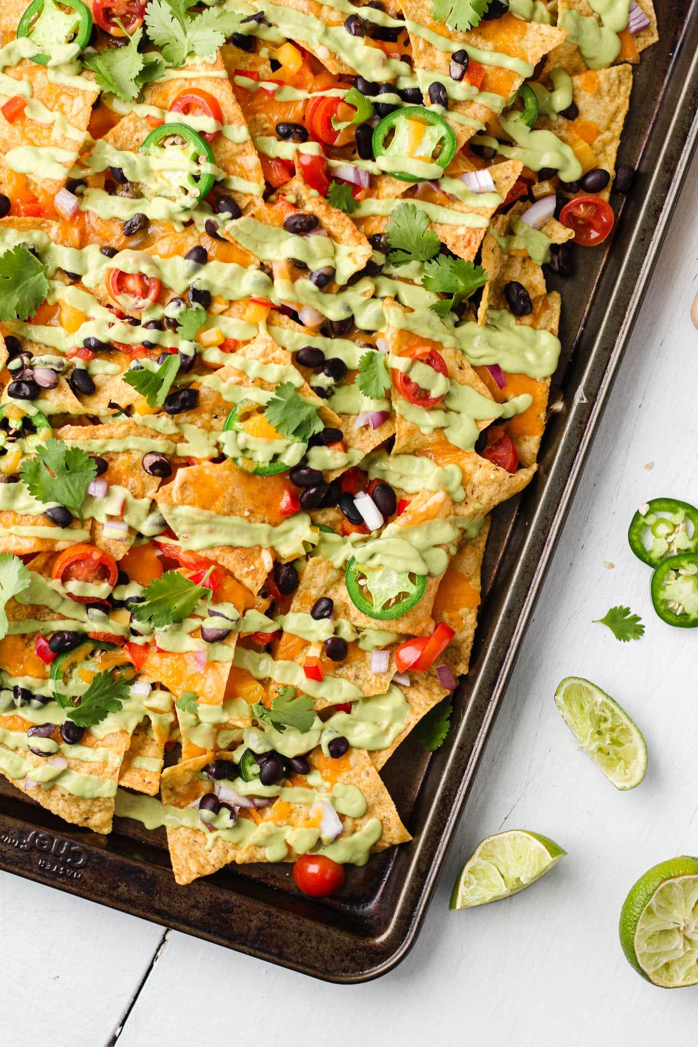 A delicious plate of nachos with various seeds and cheese, garnished with fresh herbs