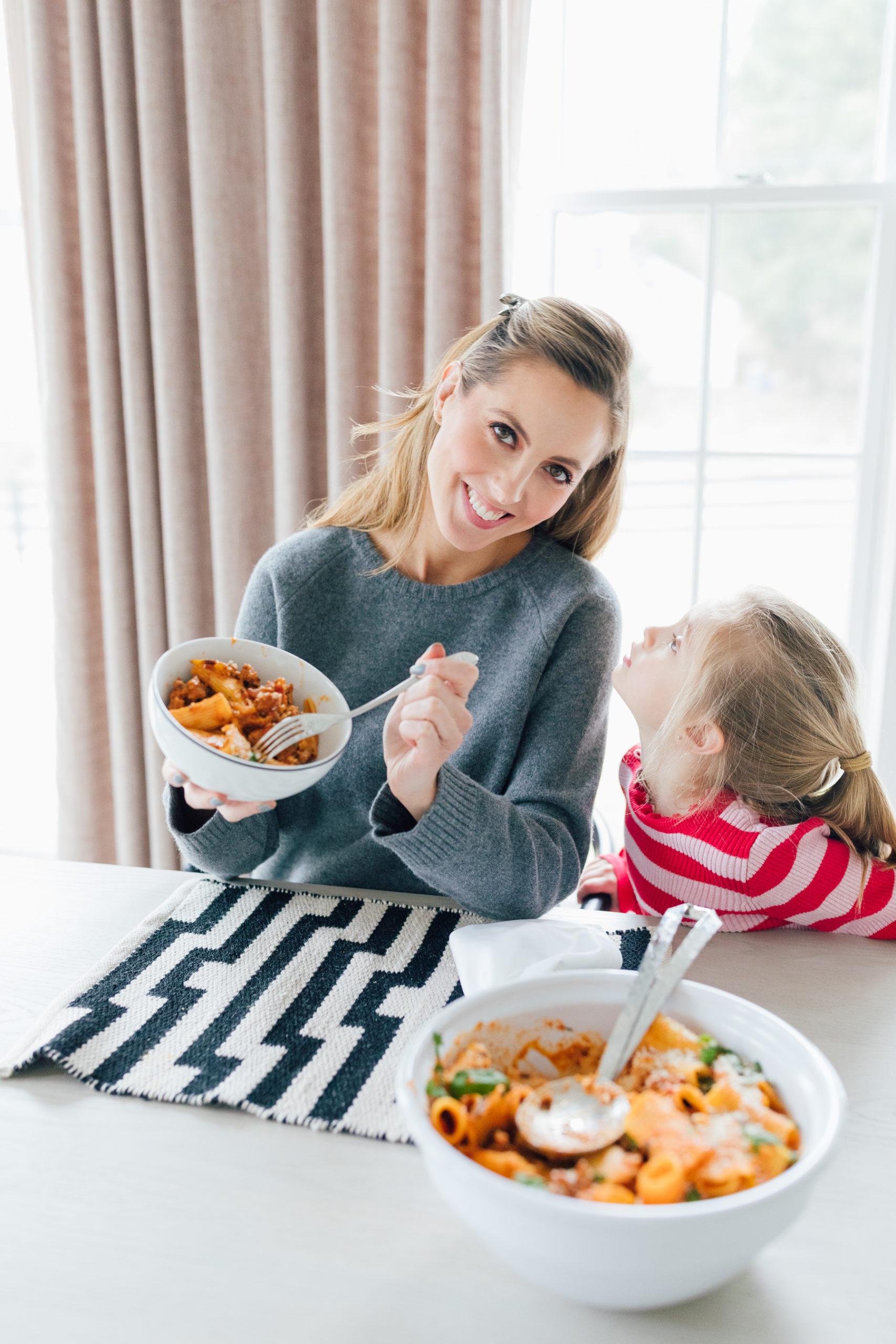 A family enjoying a meal of pasta with sausage and peppers
