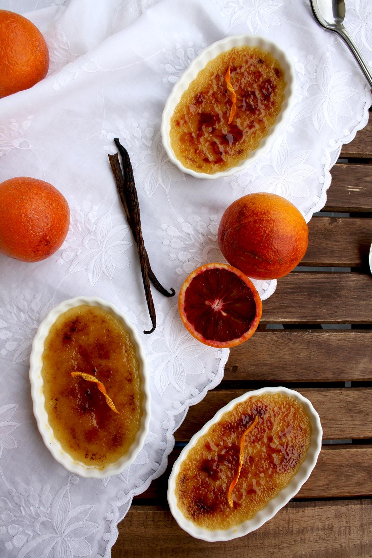 Close-up shot of blood orange crème brûlée with pistachios, ramekins on a rustic wooden table