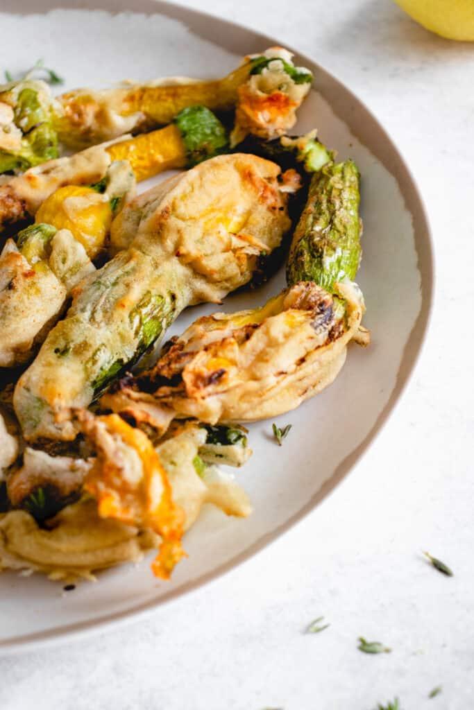 Crispy golden tempura zucchini blossoms arranged on a rustic wooden board