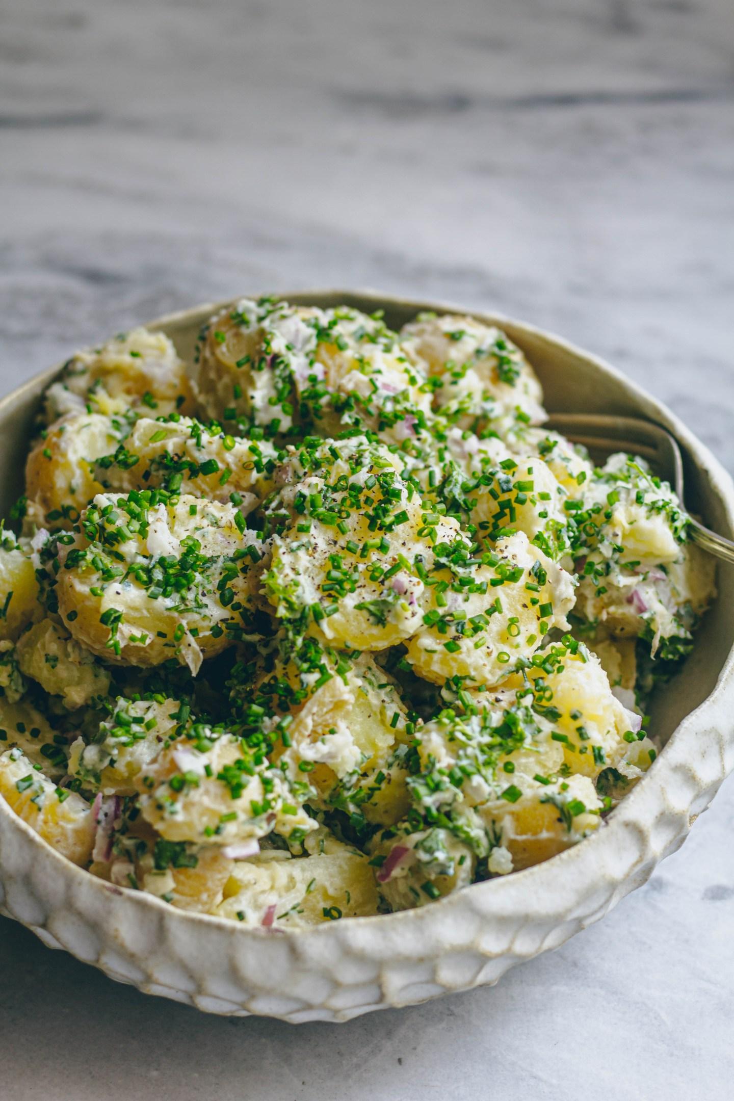 Close-up of a creamy potato salad with fresh herbs and visible potato chunks