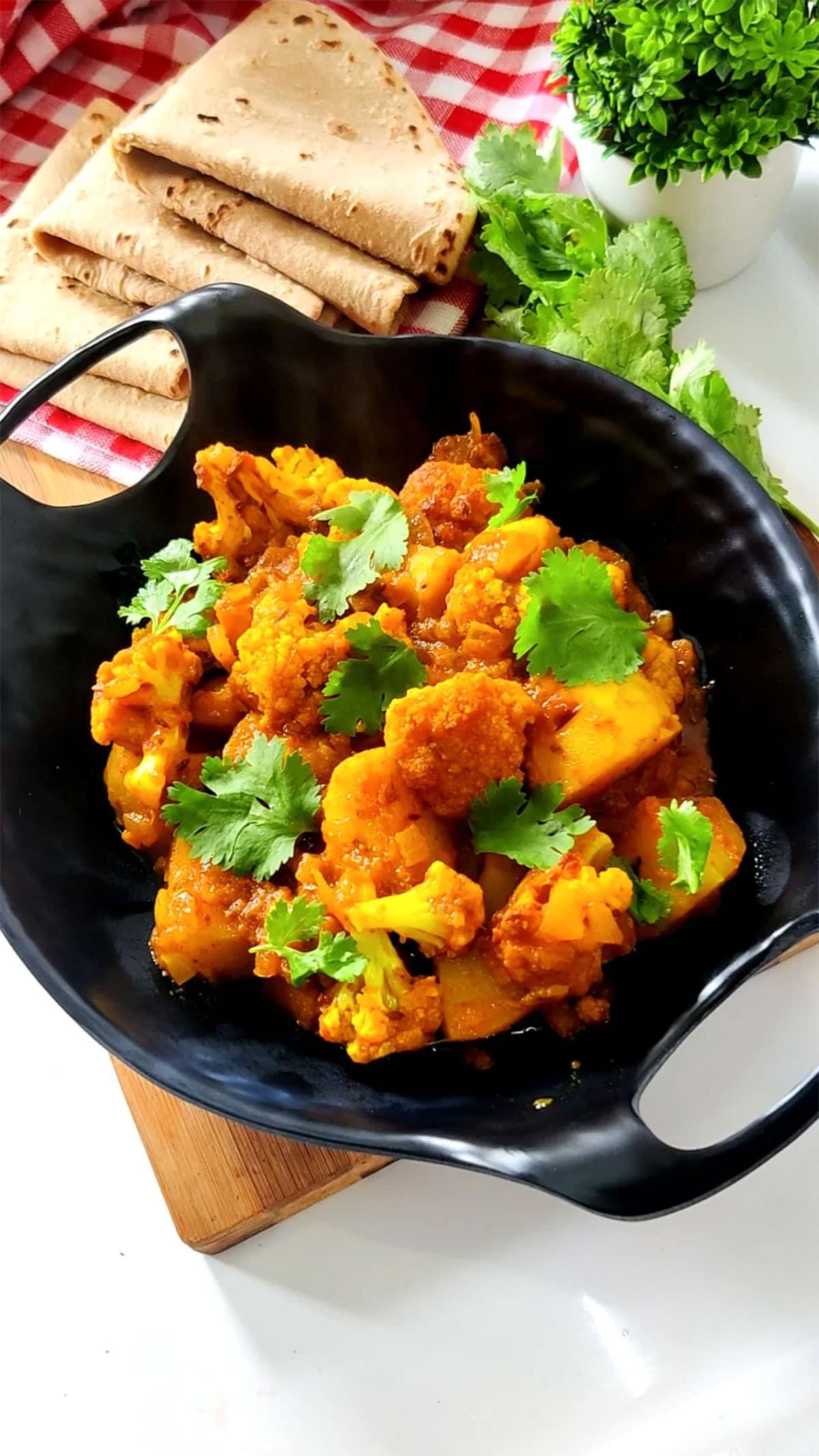 A person serving a bowl of Spicy Cauliflower & Potato Biryani to a group of friends