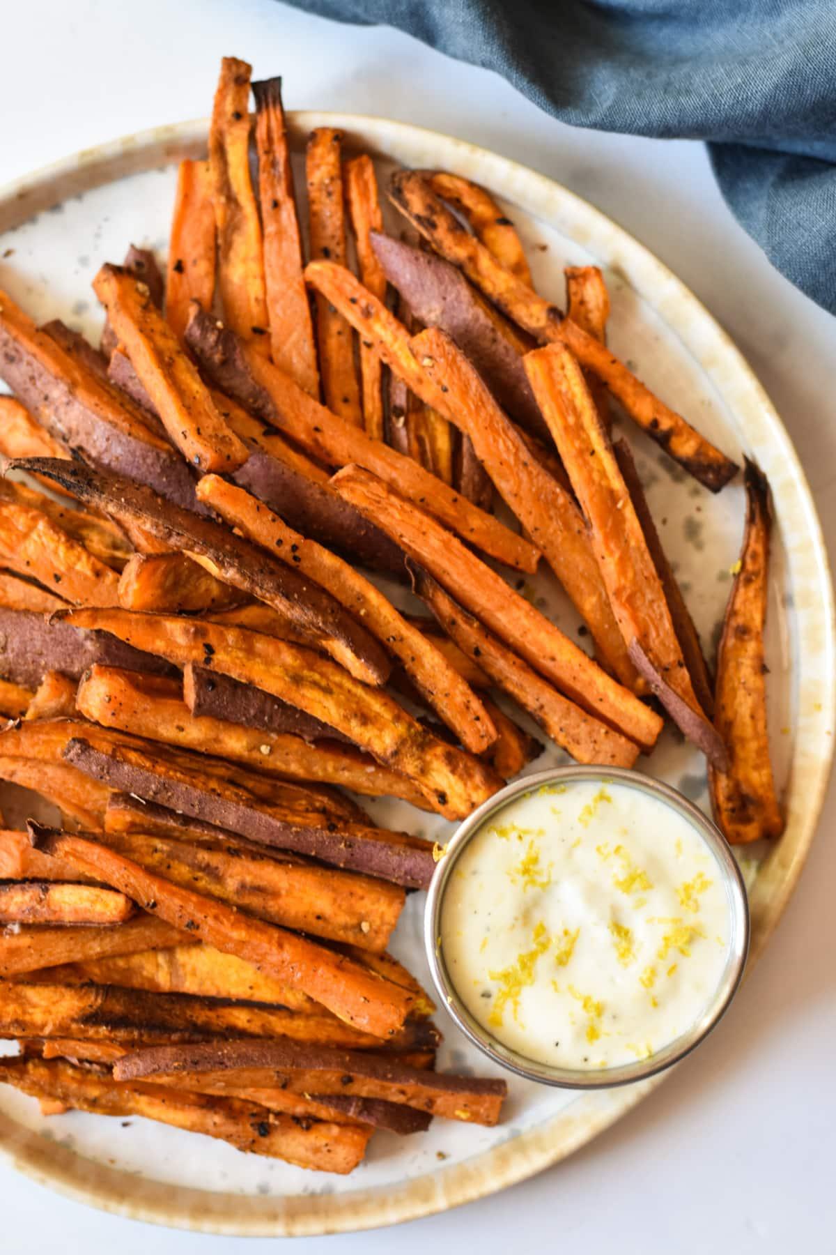 Close-up shot of perfectly grilled sweet potato fries with a bowl of creamy garlic aioli on the side