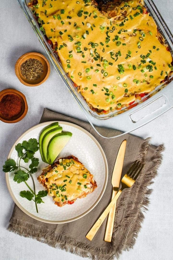 A golden-brown, bubbly cashew cheese enchilada casserole in a 9x13 inch baking dish