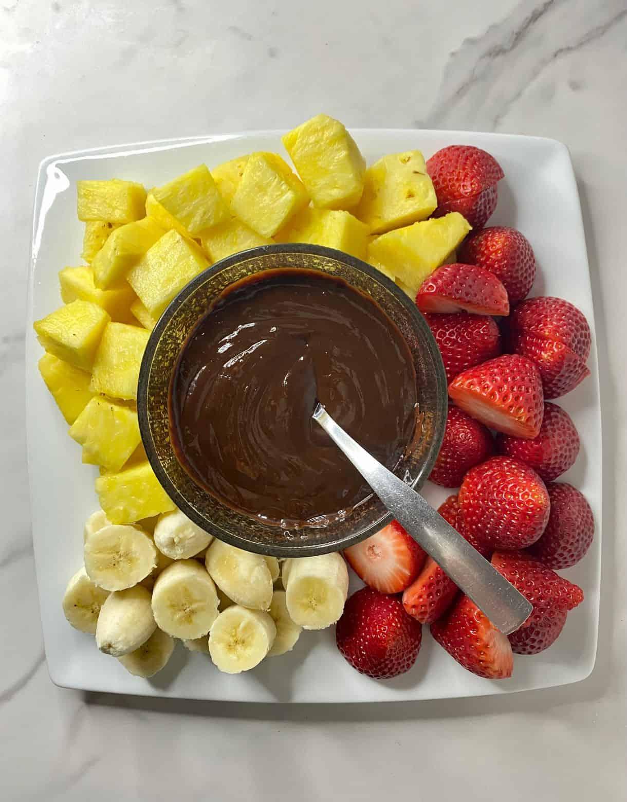 A person dipping fruit into chocolate fondue