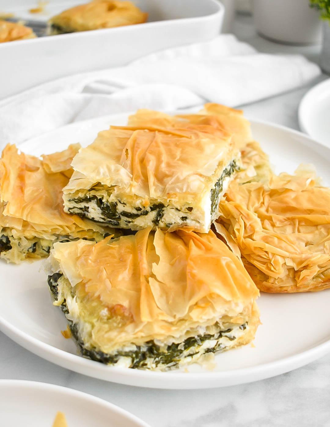 A whole Spinach & Macadamia Spanakopita on a serving platter, garnished with fresh herbs.