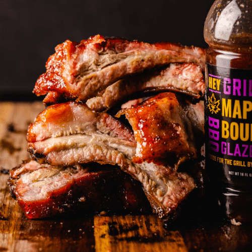 Pouring maple bourbon glaze over smoked ribs