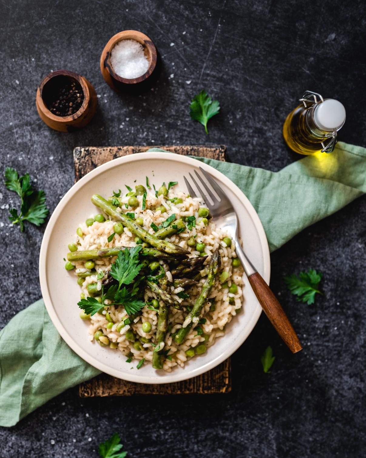 close-up shot of creamy asparagus risotto with black garlic cloves