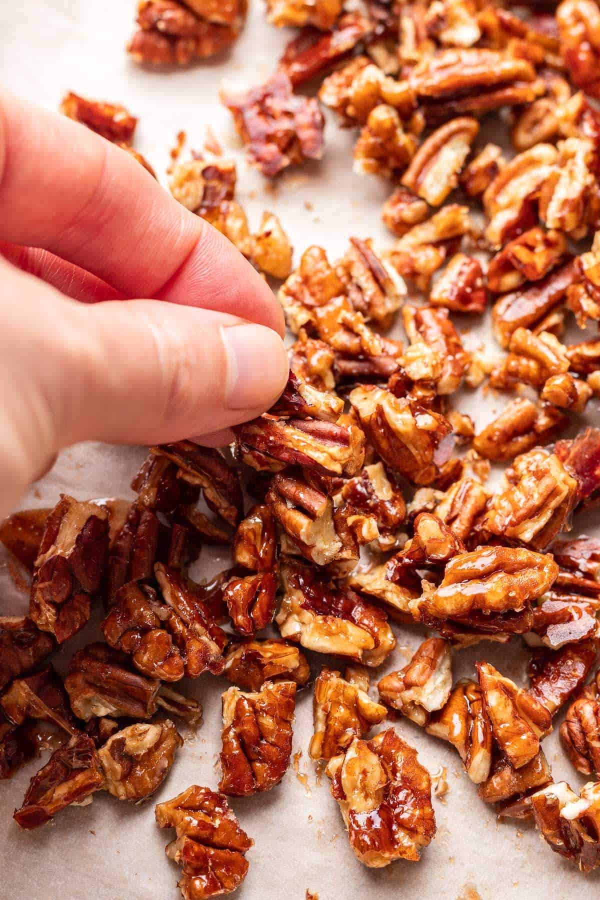 Close-up shot of glistening maple-glazed candied pecans on a baking sheet