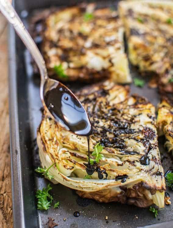 balsamic glaze being drizzled over roasted cabbage wedges